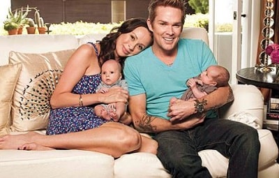 Mark cozies up with his wife and two babies in his new house.